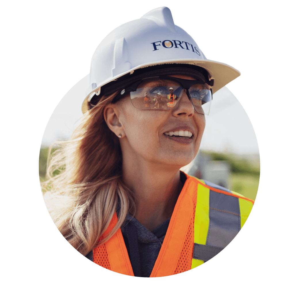 Woman with safety glasses, vest, and a Fortis hard hat