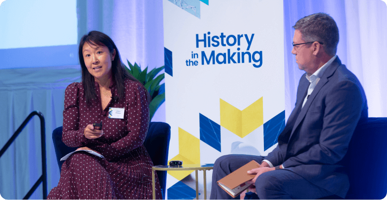 Man and woman sitting in front of a History in the Making sign