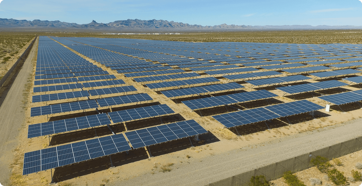 Field full of solar panels and mountains in the background